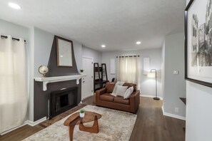 Ein Wohnzimmer mit Kamin, einem braunen Ledersofa, einem Couchtisch und einer Stehlampe.