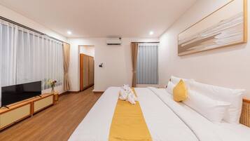 A hotel room with a bed, a television, a wall-mounted artwork, and a window with curtains.