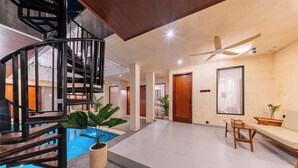 A modern interior with a spiral staircase, a pool, a ceiling fan, and a seating area. - Sekala Coliving Canggu (Tibubeneng)