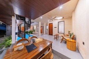 A modern interior with a wooden dining table, a spiral staircase, and a pool area.