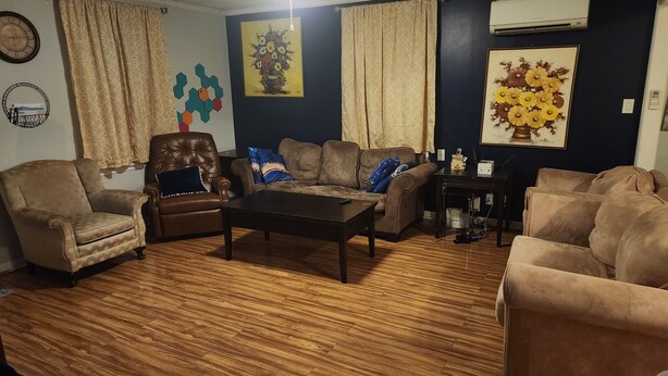 A living room with a brown leather armchair, a sofa, and a coffee table. - Cozy 2-bedroom house in charming Clarksville with AC (Clarksville)