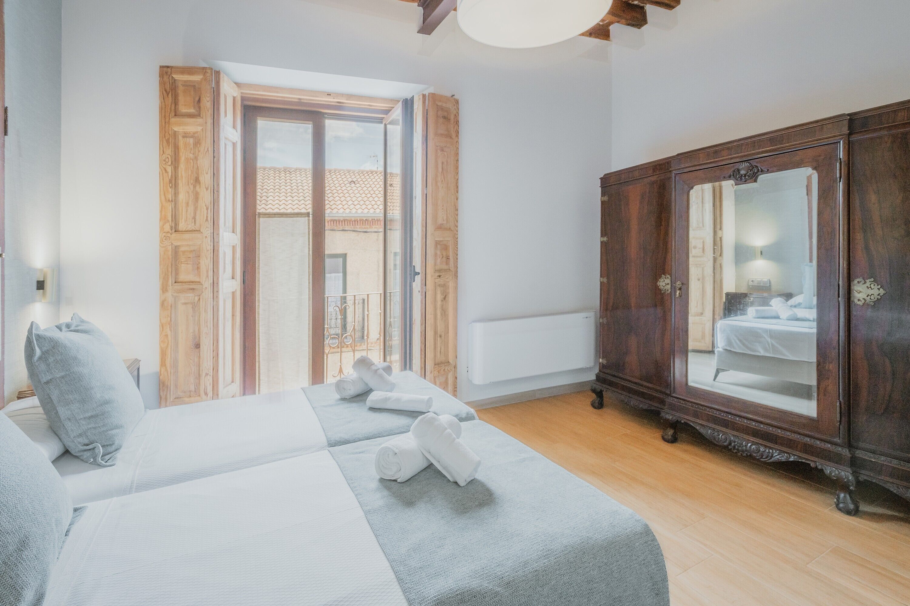 Un dormitorio con cama, armario y puerta al balcón.