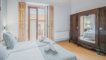Un dormitorio con cama, armario y puerta al balcón.