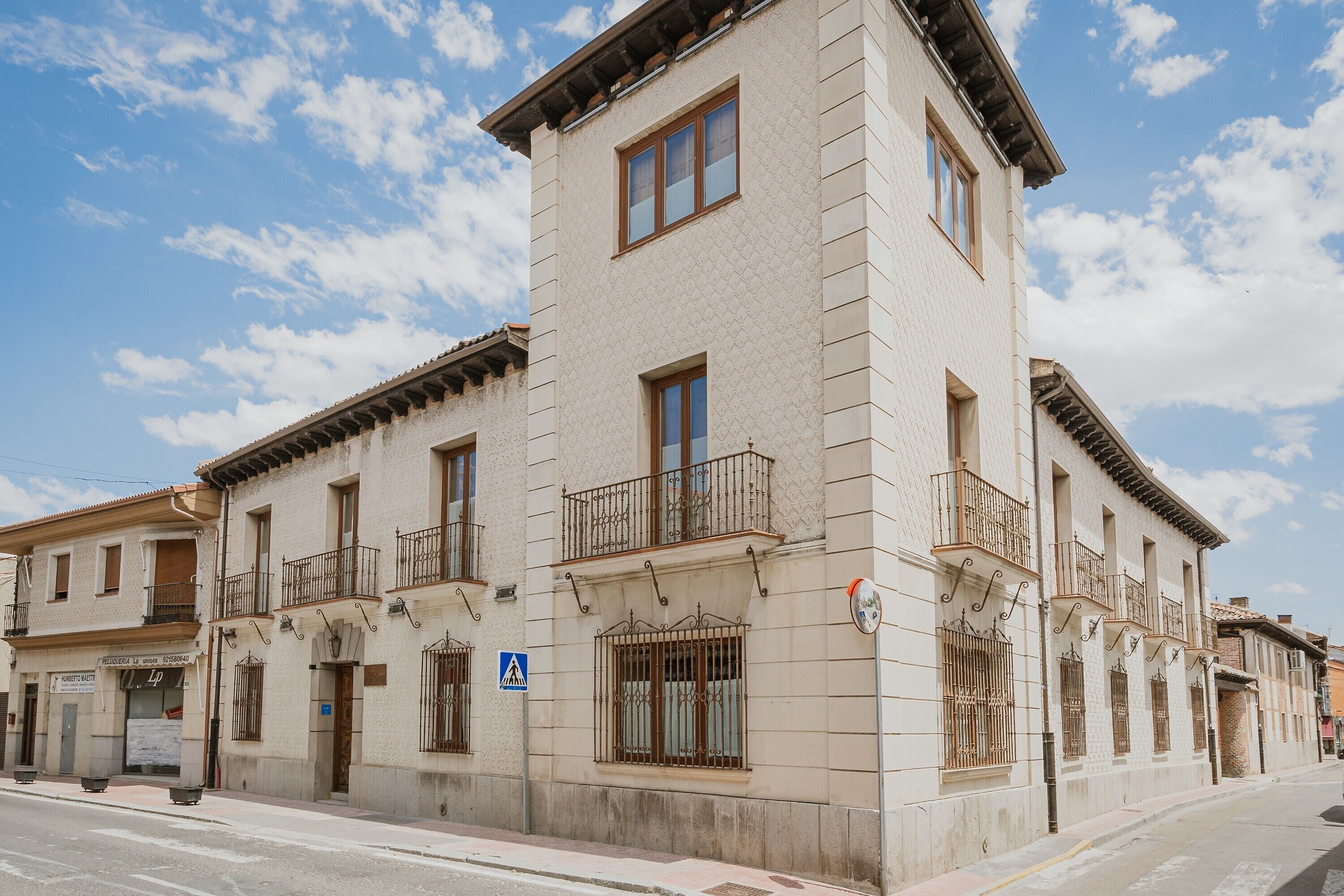 A multi-story building with balconies, a pedestrian crossing sign, and a street view.