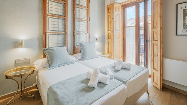 A double room with two beds, a small table, and a window with wooden shutters.