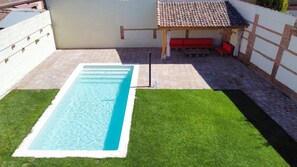 A rectangular swimming pool with clear blue water, surrounded by a well-maintained lawn and a tiled patio area. - Holiday Home 'Villa Almudena' with Private Pool, Wi-Fi and Air Conditioning (Nava de la Asunción)