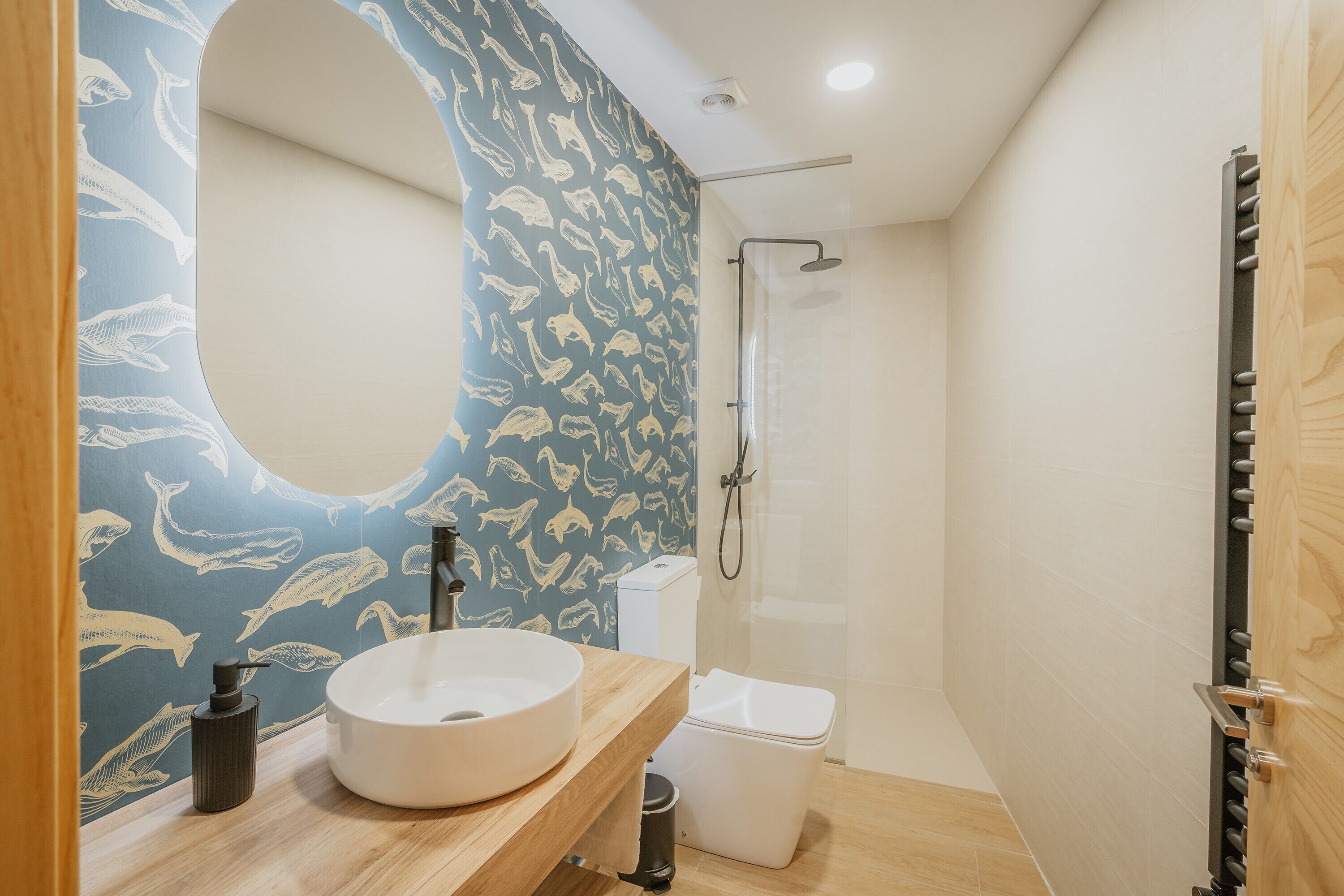 Une salle de bain avec un miroir rond, un lavabo, des toilettes et une douche.