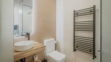 Une salle de bain moderne avec un lavabo rond, des toilettes et un porte-serviettes.