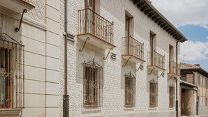 A row of white buildings with balconies, windows with metal bars, and a clear sky.