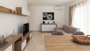 Un soggiorno moderno con televisore, divano e tavolo da pranzo.
