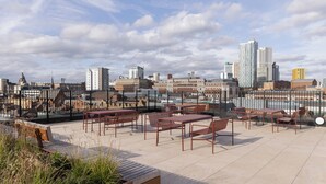 Una terrazza sul tetto con posti a sedere all'aperto, uno skyline cittadino sullo sfondo e un cielo sereno.