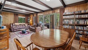 A cozy living room with a leather sofa, wooden coffee table, and a bookshelf filled with books. - Mountain Cabin w/ Hot Tub - Sleeps 6 (Peshastin)