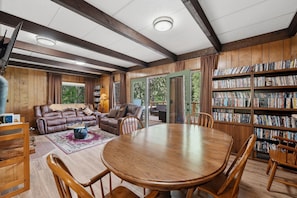 A cozy living room with a leather sofa, wooden coffee table, and a bookshelf filled with books. - Mountain Cabin w/ Hot Tub - Sleeps 6 (Peshastin)