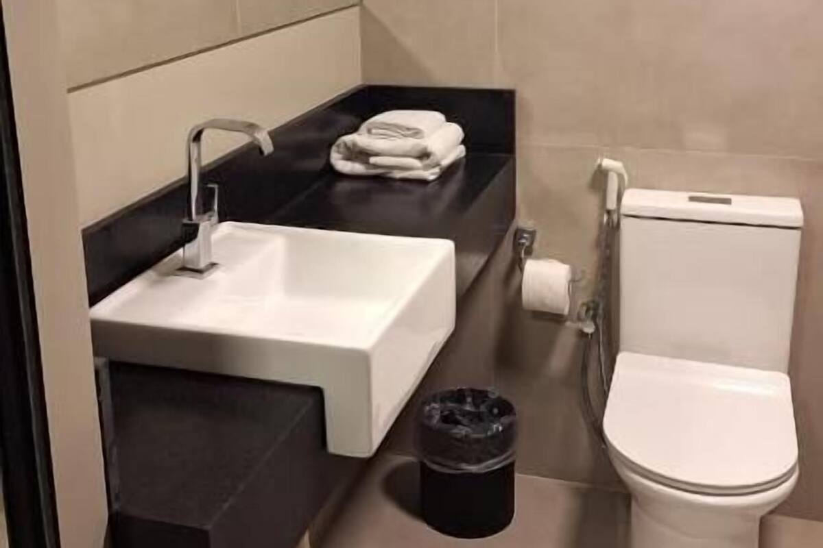 A bathroom with a white sink, black countertop, and a toilet.