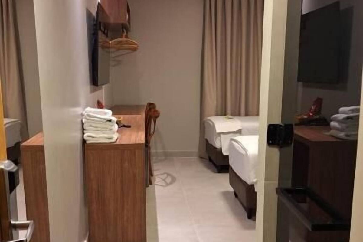 A hotel room with a desk, two beds, a TV, and a bathroom.