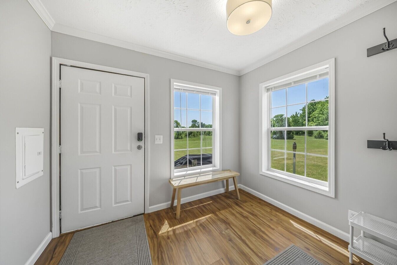 A room with a door, two windows, a bench, and a light fixture.