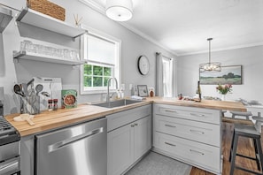 Une cuisine moderne dotée d’appareils électroménagers en acier inoxydable, d’un plan de travail en bois et d’une grande fenêtre.