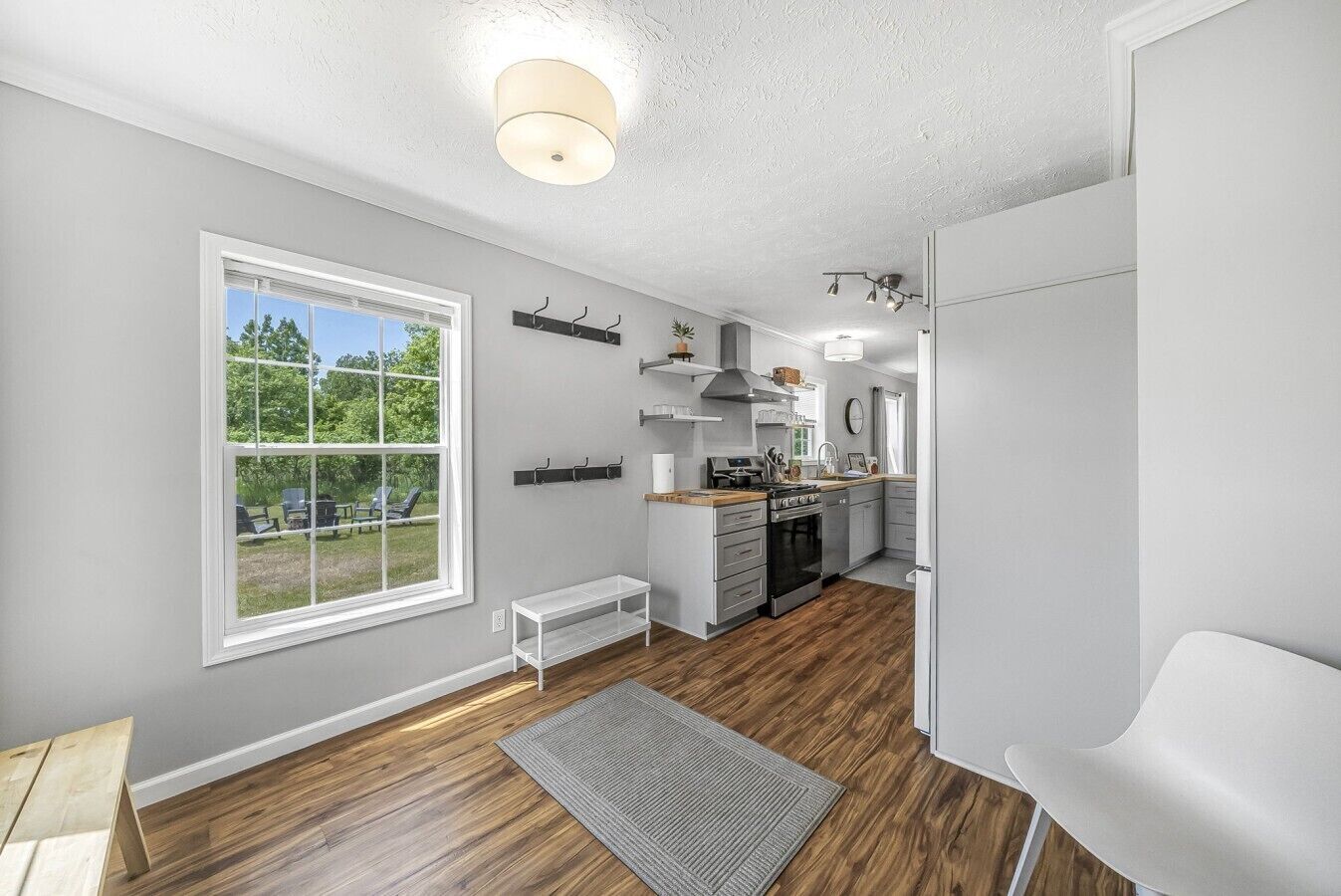 A modern kitchen with a large window, a built-in oven, and a white chair.