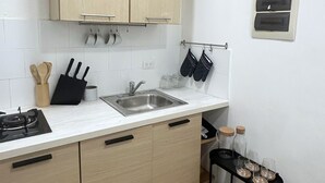 Eine Küche mit Holzausstattung, einem Spülbecken, einem Herd und einem kleinen, schwarzen Regal mit Gläsern.