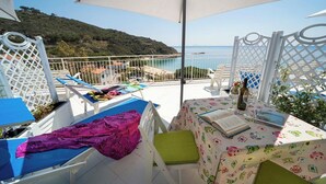 Een balkon met een tafel, stoelen en uitzicht op zee.