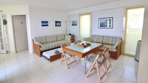 A living room with a sofa set, a glass-top dining table, and a chair. - Seafront Terrace & Wi-Fi [600m from station]. (Menton)