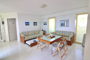 A living room with a sofa set, a glass-top dining table, and a chair. - Seafront Terrace & Wi-Fi [600m from station]. (Menton)