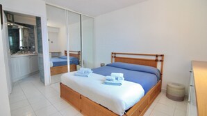 A bedroom with a bed, a mirror, a wardrobe, and a bathroom visible through an open door. - Seafront Terrace & Wi-Fi [600m from station]. (Menton)