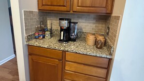 Una cucina con mobili in legno, un piano di lavoro in granito e una macchina per il caffè.