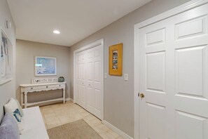 A hallway with a white console table, a framed picture, and a closed door. - Sun Realty pet-friendly oceanside Duck home w/ pool, hot tub & sound views (Duck)