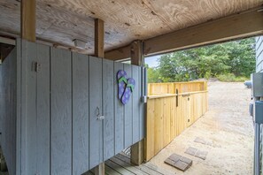 A covered outdoor area with a wooden deck, a wooden fence, and a concrete structure. - Sun Realty pet-friendly oceanside Duck home w/ pool, hot tub & sound views (Duck)