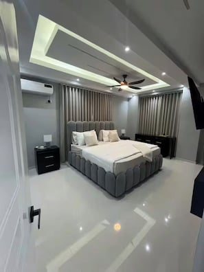 Un dormitorio moderno con una cama grande, ventilador de techo y aire acondicionado integrado.