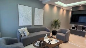 A modern living room with a sofa, armchairs, a coffee table, and a TV. - Marcial Luxury Apartments - Apt 2A (Baní)