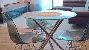 A modern living room with a glass table, clear chairs, a sofa, and a TV. - Legacy Unit - Central Yet Serene - Pool & Fast WiFi (Plum)