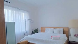 A bedroom with a bed, bedside table, and a window with curtains. - Legacy Unit - Central Yet Serene - Pool & Fast WiFi (Plum)