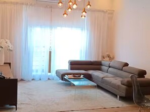 A modern living room with a sofa, a coffee table, and a hanging light fixture. - Legacy Unit - Central Yet Serene - Pool & Fast WiFi (Plum)