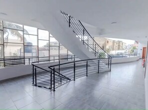 A spacious interior with a curved staircase, large windows, and a tiled floor. - Legacy Unit - Central Yet Serene - Pool & Fast WiFi (Plum)