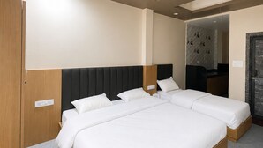A hotel room with a large bed, a wooden wardrobe, a mirror, and a ceiling light. - Hotel Bhawani (Udaipur)