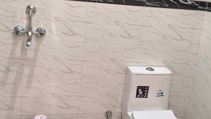 A bathroom with a toilet, a bidet, and a wall-mounted showerhead. - Hotel Bhawani (Udaipur)