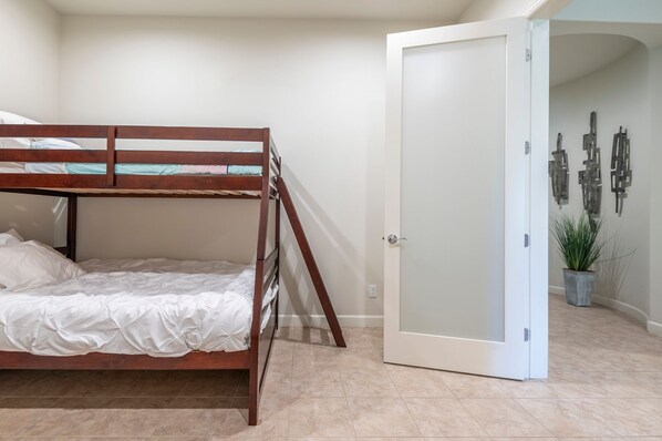 A bunk bed in a room with a white door and a wall with abstract art.