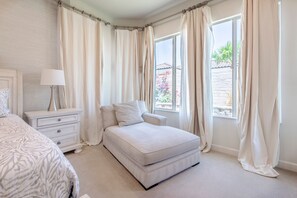 A bedroom with a bed, bedside table, lamp, and curtains. - Sleek Mid-Century Style Home in Rancho Mirage (Rancho Mirage)