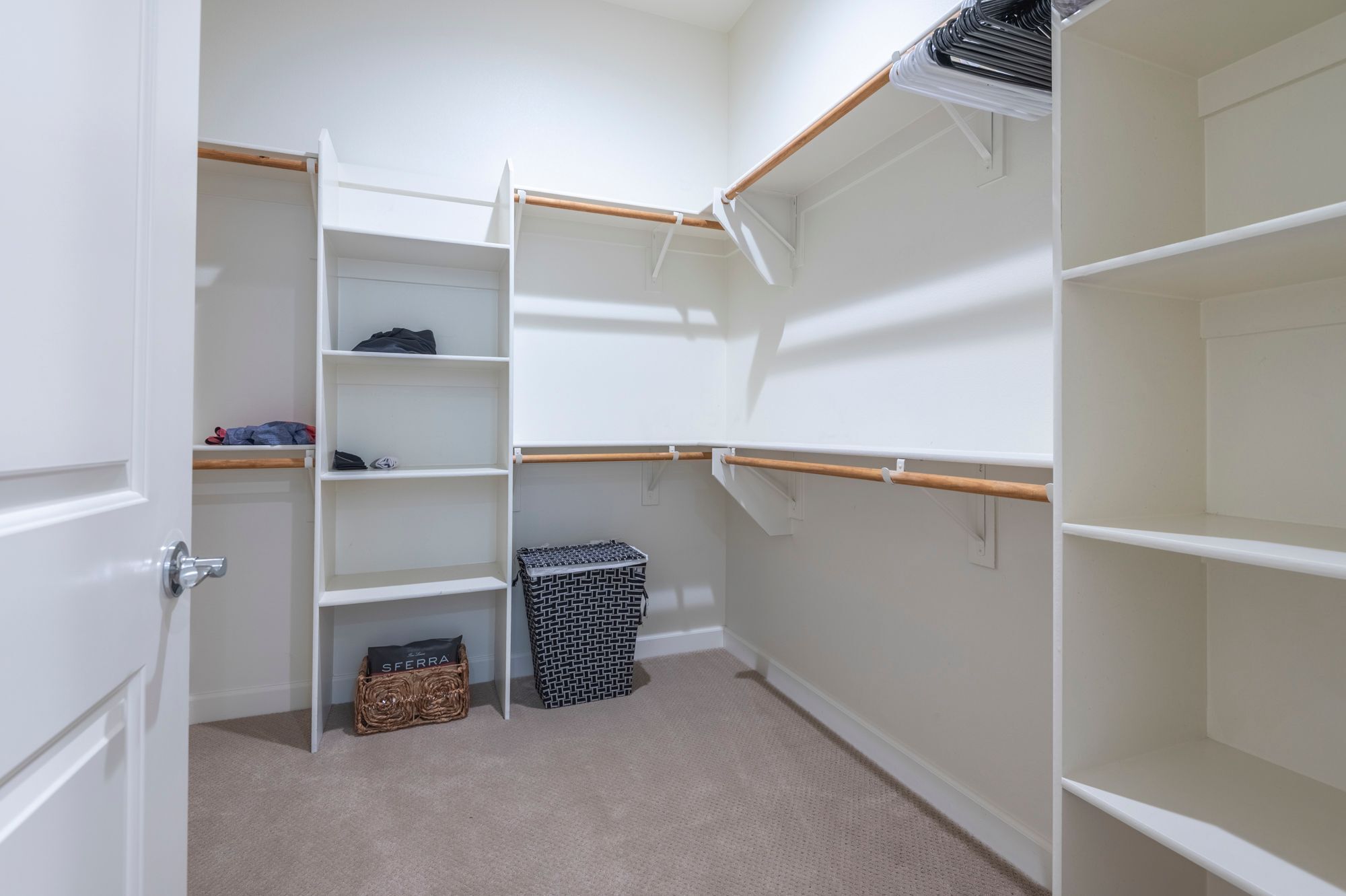 A corner closet with open shelves, a hanging rod, and a wicker basket.