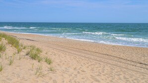 Een zandstrand met zachte golven en heldere lucht.