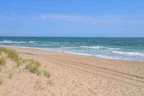 Ein sandiger Strand mit sanften Wellen und blauem Himmel.