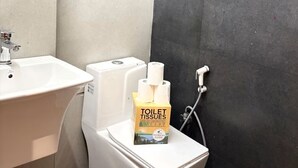 Une salle de bain avec un lavabo, des toilettes et un miroir. Il y a du papier toilette sur les toilettes.
