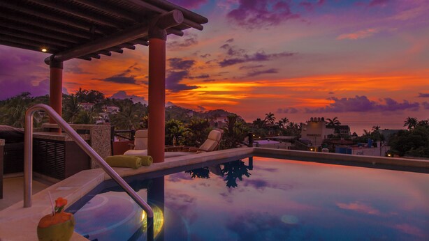 Ein Pool mit Sonnenuntergangsblick, Liegestühle und eine Pergola.