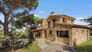 A stone house with a covered porch and a pathway leading to the entrance. - Villa 'Can Ayala' Arenys de Munt – With Garden and Private Pool. (Collsacreu)