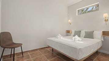 Habitación de hotel con cama, una silla, una lámpara de pared y una ventana con vistas.