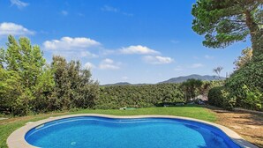 A swimming pool with a curved edge, surrounded by well-maintained grass and trees. - Villa 'Can Ayala' Arenys de Munt – With Garden and Private Pool. (Collsacreu)