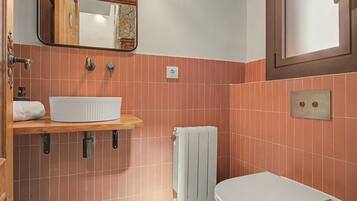 A bathroom with a white sink, a towel rack, a toilet, and a mirror.