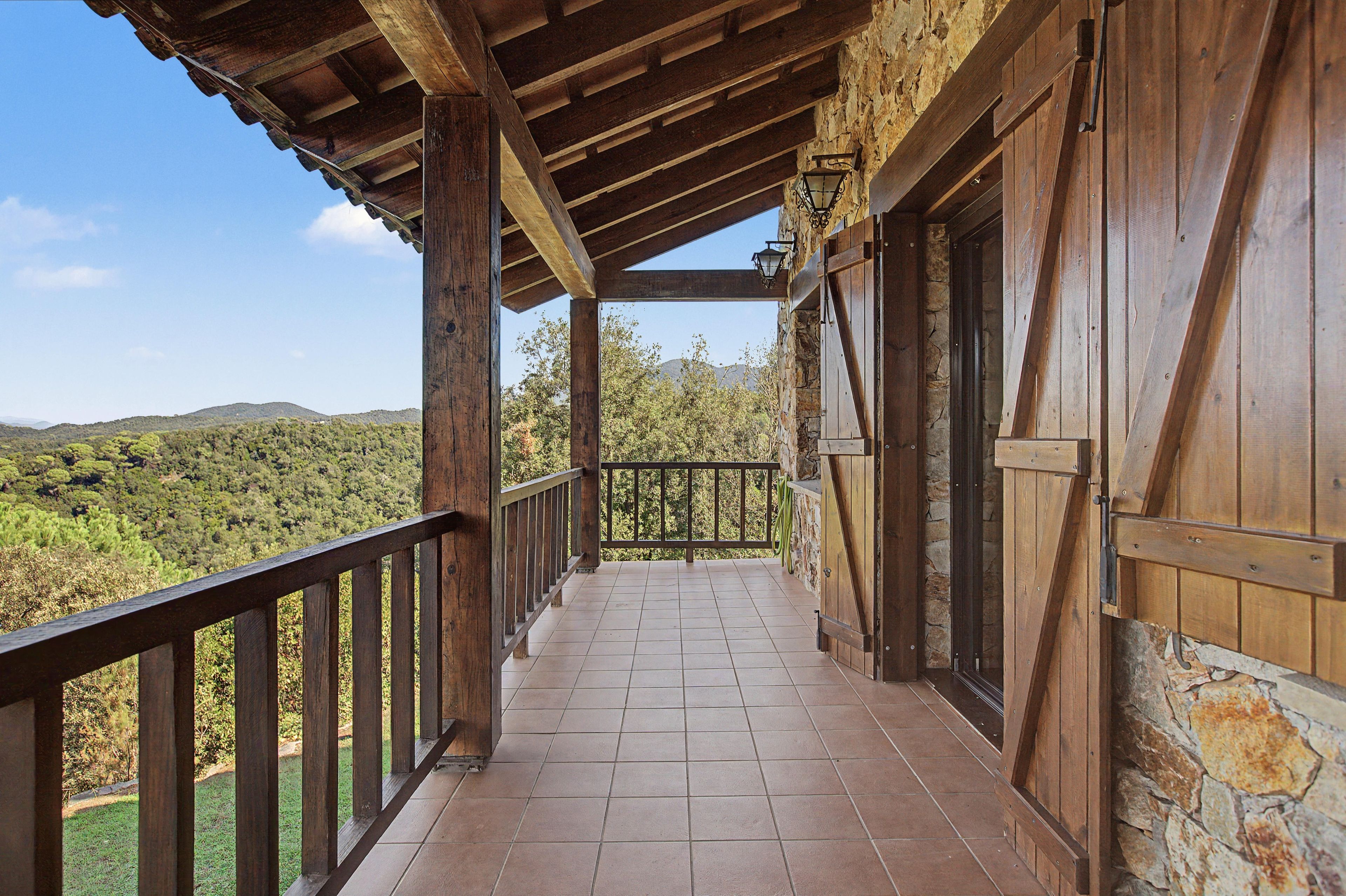 Un balcón de madera con piso de baldosas, con vistas a un paisaje montañoso.